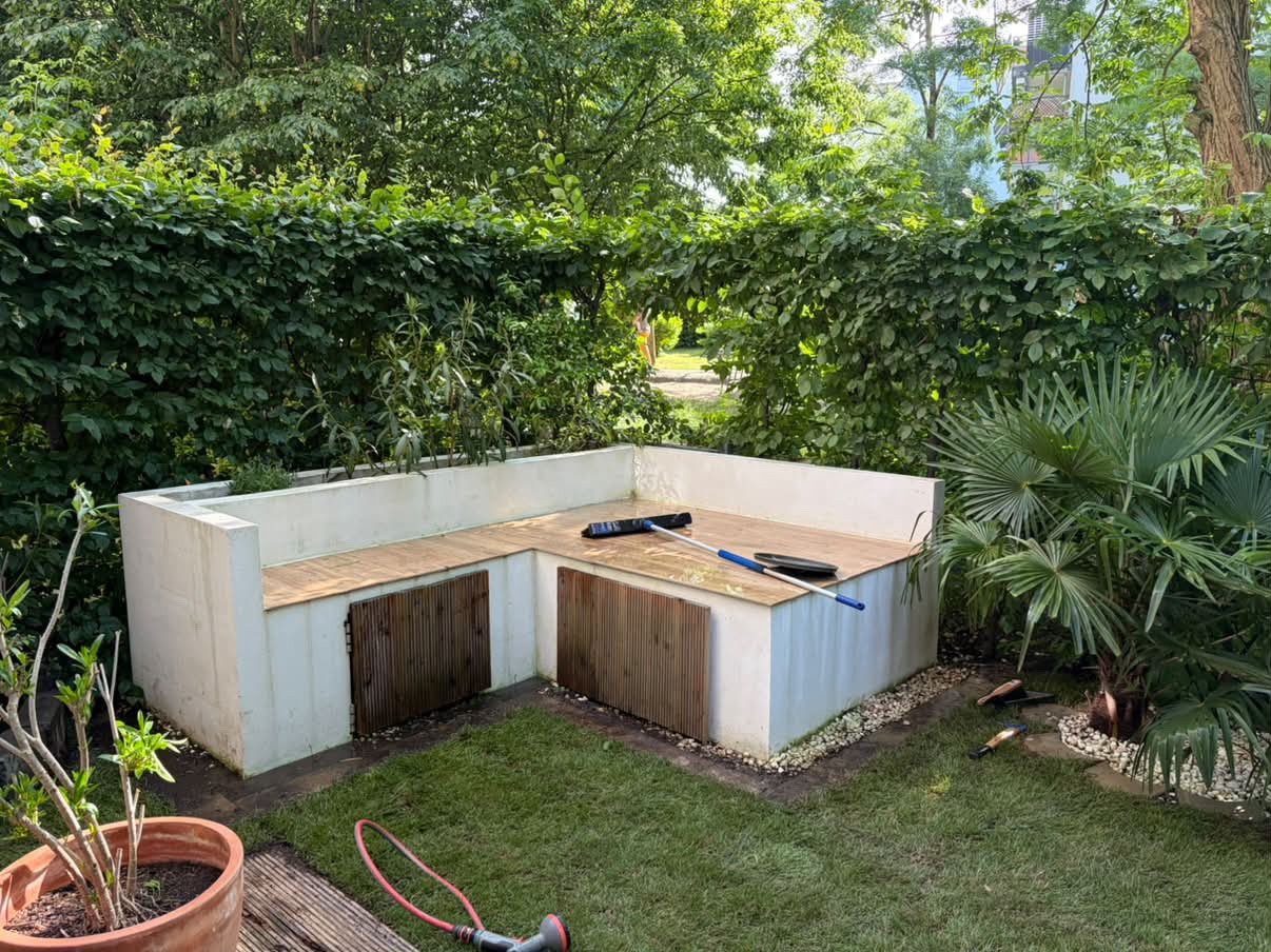 Gemauerte Sitzecke mit Holzauflage im gepflegten Garten